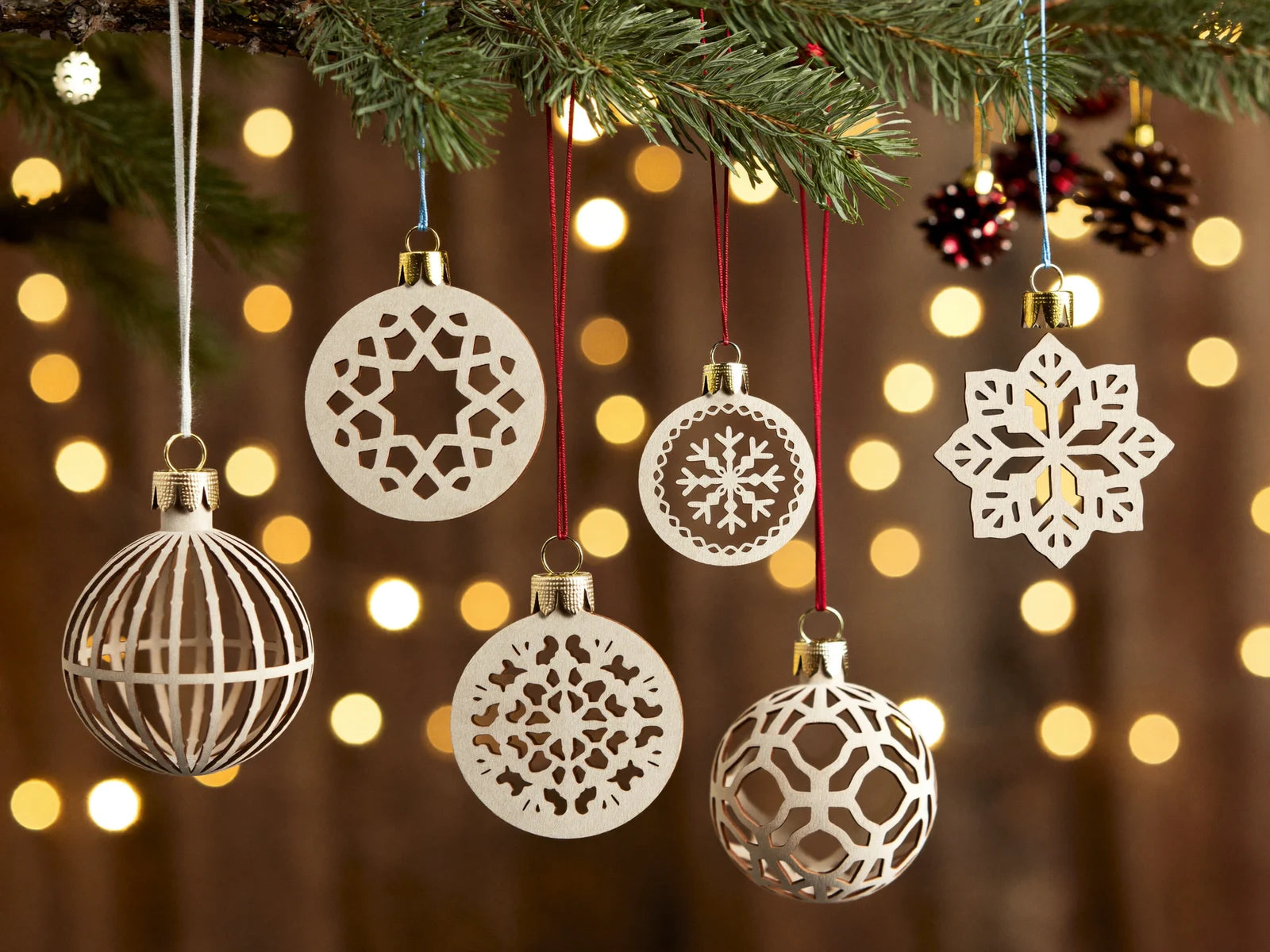 Laser-cut wooden holiday ornaments hanging on a tree.